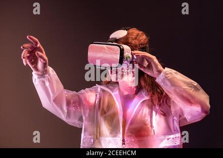 Young unrecognizable Woman touching air and wearing virtual reality headset in studio Stock Photo