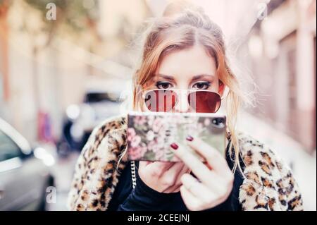 Young blonde Woman applying lipstick in madrid streets, Spain Stock Photo