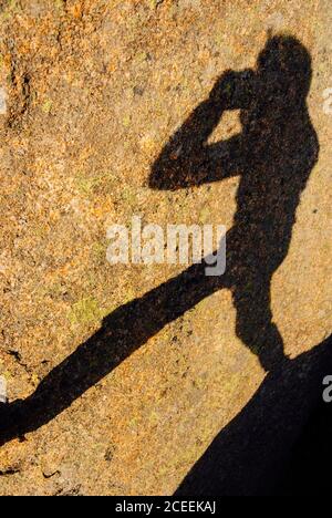 Shadow of photographer man standing and on stones and taking shots. Stock Photo