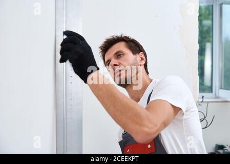 Male worker plastering a wall using a long spatula. Renovation concept Stock Photo