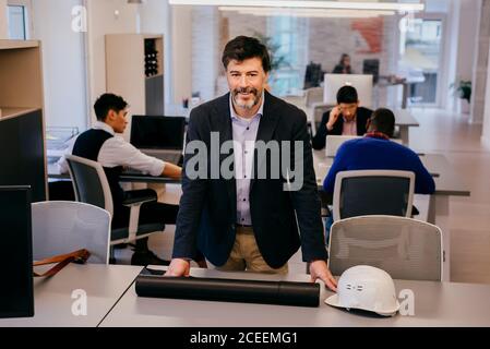 Handsome adult man sitting on table in office Stock Photo