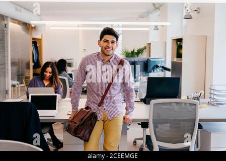 Smiling man leaning on table in office Stock Photo