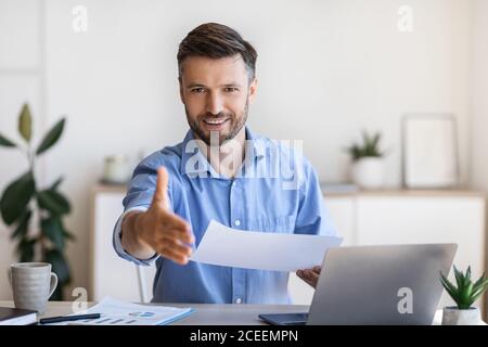 Job Interview. Friendly male HR manager extending hand for handshake at camera Stock Photo