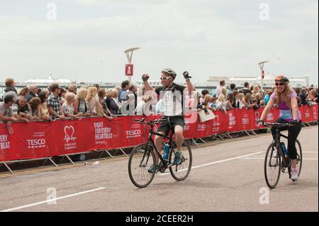 Riders cross the finish line after cycling from London to Brighton for the British Heart Foundation's famous L2B fundraising bike ride. Stock Photo