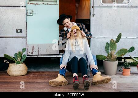 Attractive young man and Woman smiling while sitting near shabby camper together Stock Photo