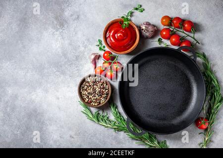 Cast iron pan and spices on a concrete background with copy space. Empty iron pan. Stock Photo