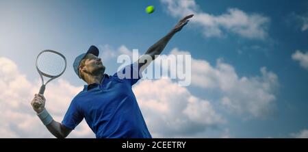male tennis player hitting ball with racket against blue sky. banner copy space Stock Photo