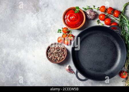 Cast iron pan and spices on a concrete background with copy space. Empty iron pan. Stock Photo
