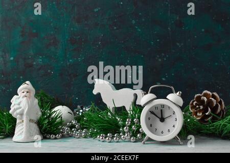 Christmas composition with pine branches and white Christmas decorations and a clock on a cosmic background Stock Photo
