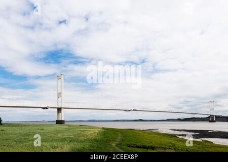 Path beside Severn River Estuary with span of old Severn Bridge carrying the M48 motorway. Beachley, Gloucestershire, England, UK, Britain Stock Photo