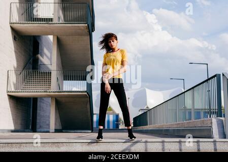 Pretty young Woman in sportswear standing on the street and looking at camera. Stock Photo
