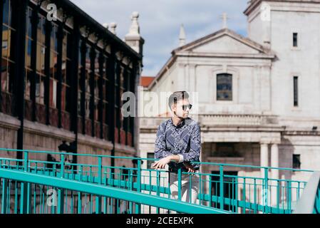 Handsome man leaning on fence on street Stock Photo