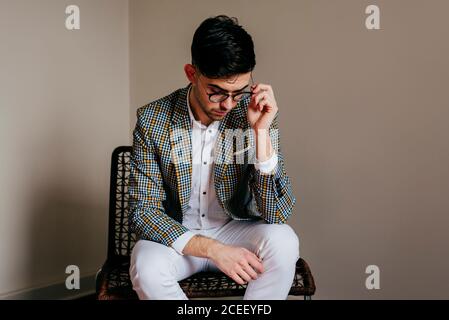 Thoughtful stylish young man on chair Stock Photo