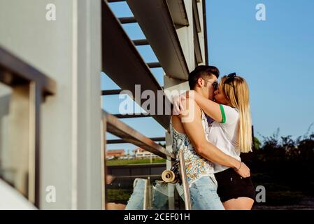 Young couple embraced and posing near skateboard Stock Photo