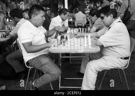 SANTIAGO, CHILE - Dec 23, 2017: Two middle-aged men playing chess outdoors in a square surrounded by other chess playing pairs of people. Santiago, Ch Stock Photo