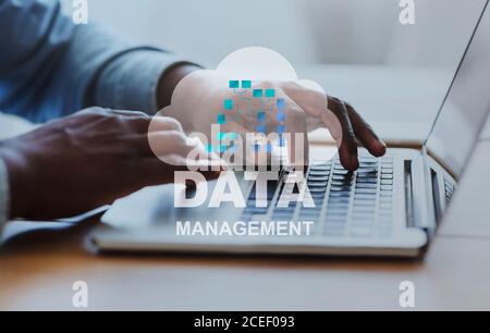 Data Management Concept. Black Businessman Working On Laptop In Office, Analyzing Information Stock Photo