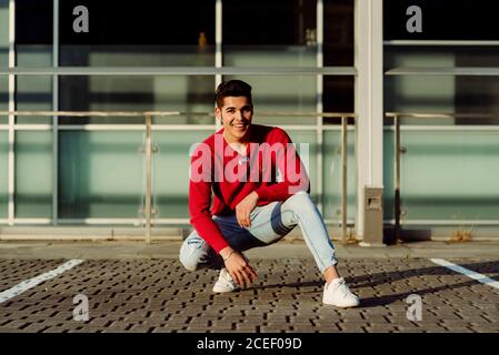 Attractive young man squatting in city Stock Photo