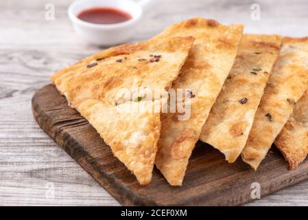 Taiwanese food - delicious flaky scallion pie pancakes on bright wooden table background, traditional snack in Taiwan, close up. Stock Photo