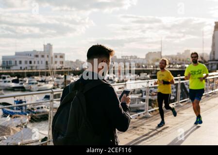 Stylish dreaming man on pier with smartphone Stock Photo