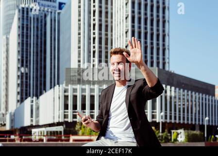 man browsing smartphone on bench and greeting Stock Photo