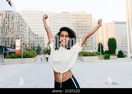Laughing African-American Woman on street hands up Stock Photo