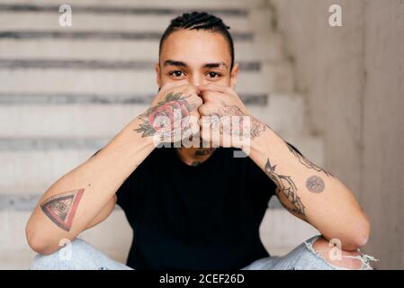 Hipster covering face with tattooed hands Stock Photo
