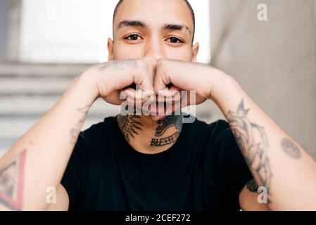 Hipster covering face with tattooed hands Stock Photo