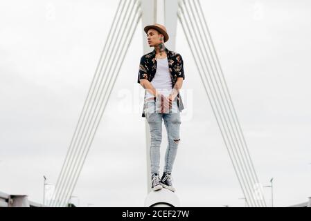 Hipster standing on railing of bridge Stock Photo