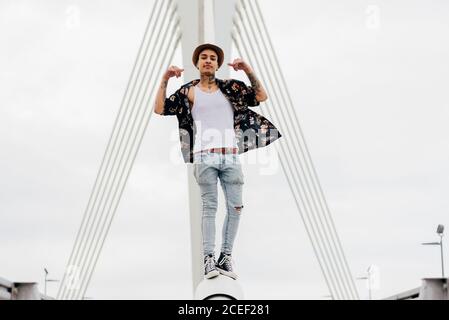 Hipster standing on railing of bridge Stock Photo
