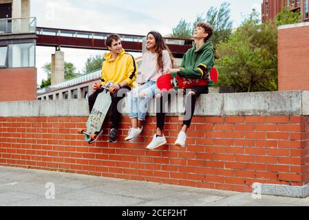 Teenagers with skateboards on fence Stock Photo