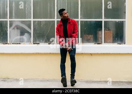 Serious young black male wearing red jumper outdoors Stock Photo
