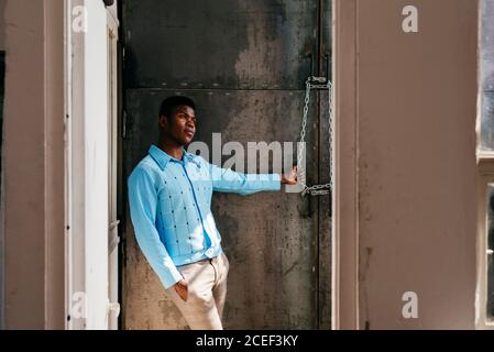 African-American man looking out dirty window Stock Photo