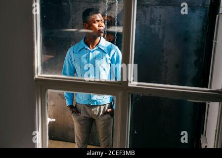 African-American man looking out dirty window Stock Photo