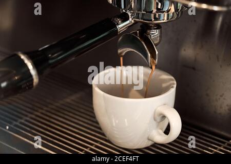 Close-up coffee pouring to white cup from professional coffee making machine Stock Photo
