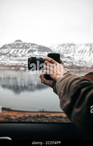 Side view of crop professional photographer taking shots with camera at lake in hills in the Iceland Stock Photo