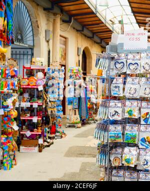 LARNACA, CYPRUS - FEBRUARY 16, 2019: Colorful gifts magnets, kitchen towels on stands at souvenir market in Larnaca touristic downtown Stock Photo