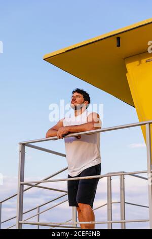 Man leaning on railing of beach hut at seaside, Southwold, Suffolk, UK ...