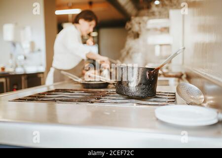 The black pot on a stove in the restaurant kitchen. Horizontal indoors shot. Stock Photo