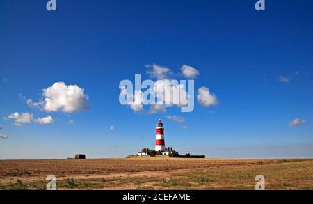 A view of the independently operated lighthouse against a blue sky with white clouds on the North Norfolk coast at Happisburgh, Norfolk, England, UK.