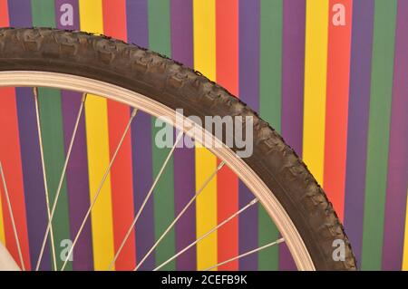 Bicycle tire in foreground showing rays, defocused multicolored background, selective focus, photo style texture or scene background. Stock Photo