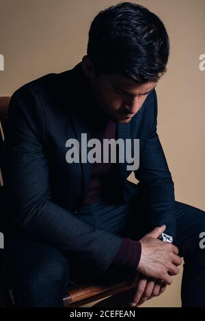 Young thoughtful business man in a studio seating in a chair Stock Photo