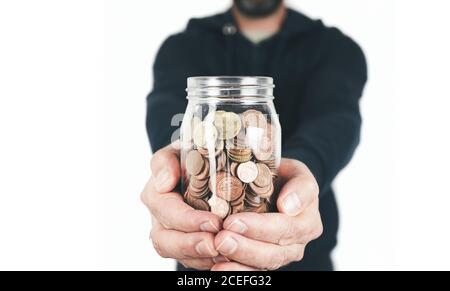 front view of man holding jar filled with coins against white background Stock Photo