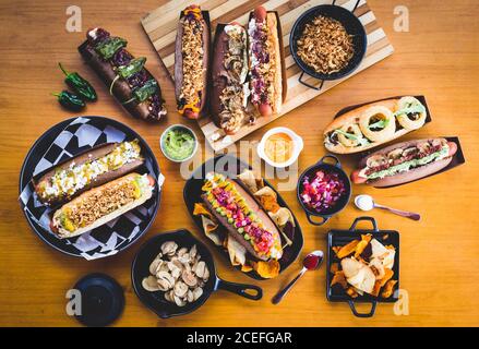 Flat lay of great amount of delicious food of hot dogs and snacks served on wooden table. Stock Photo
