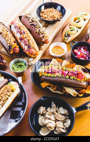 Flat lay of great amount of delicious food of hot dogs and snacks served on wooden table. Stock Photo