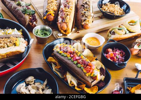 Flat lay of great amount of delicious food of hot dogs and snacks served on wooden table. Stock Photo