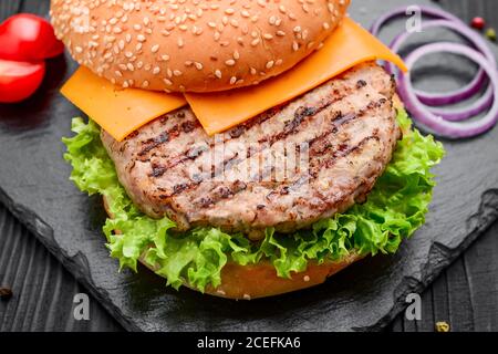Homemade burger with salad and cheese. Laid out on black slate Stock Photo