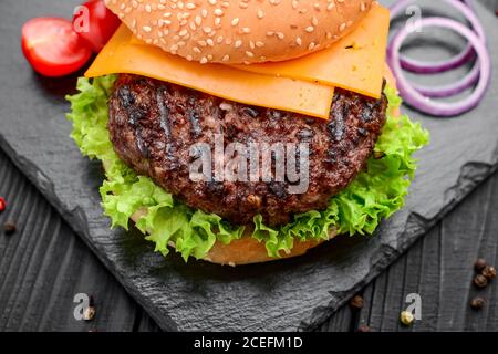 Homemade burger with salad and cheese. Laid out on black slate Stock Photo