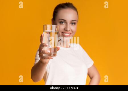 Glass of clean mineral water in hands of smiling young woman Stock Photo