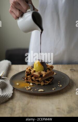 Woman pouring chocolate sauce on waffles Stock Photo