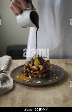 Woman pouring chocolate sauce on waffles Stock Photo